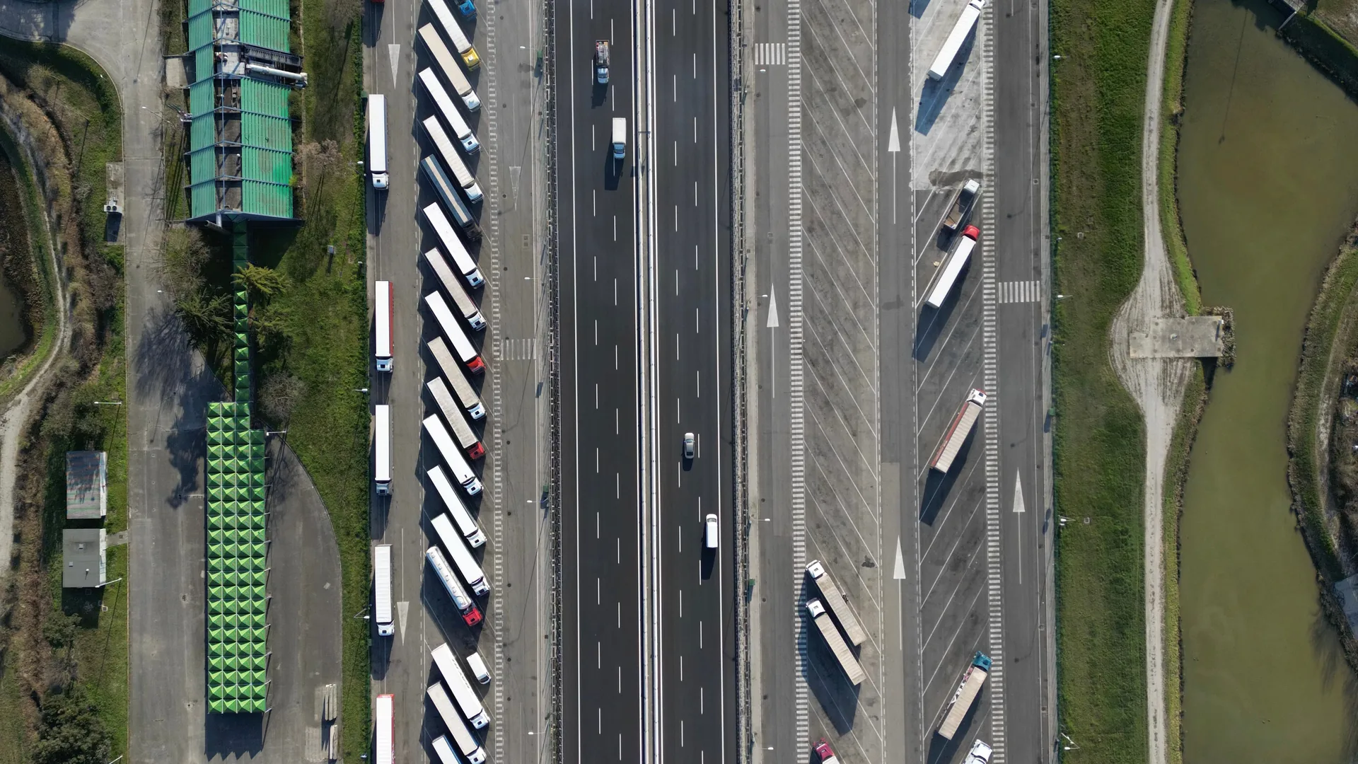 Luchtfoto van een snelweg met vrachtwagens en aangrenzende parkeerplaatsen.